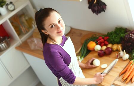Young woman cutting vegetables in the kitchen .の写真素材