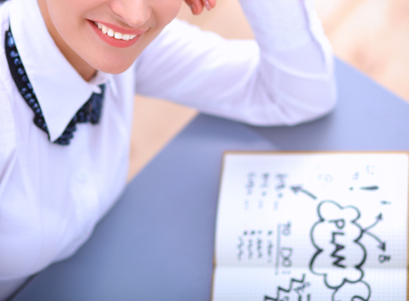 Young woman writes to diary on a white table .の写真素材