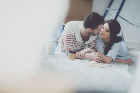 Couple choosing paint colour from swatch for new home lying on wooden floorの写真素材