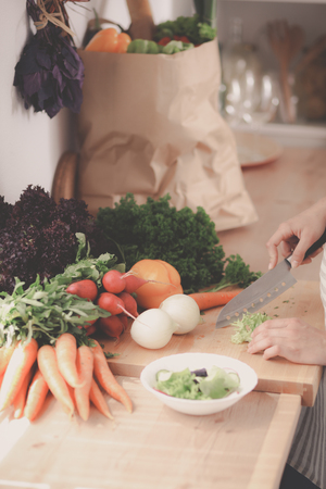 Young woman cutting vegetables in the kitchenの写真素材
