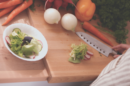 Young woman cutting vegetables in the kitchenの写真素材