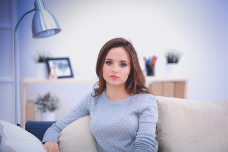 Portrait of happy young woman sitting on sofaの写真素材