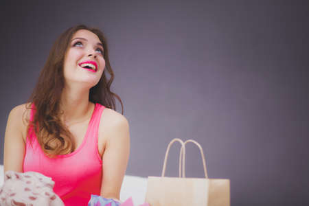 Pretty young woman sitting a bed with shopping bags after successful shoppingの写真素材