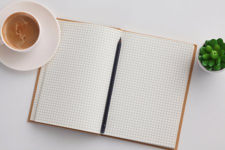 Top view image of open notebook with blank pages next to cup of coffee on wooden tableの写真素材