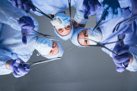 Surgeons team, woman wearing protective uniforms,caps and masks.の写真素材