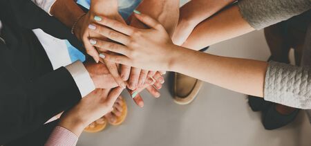 Portrait of people with various occupations putting their hands on top of each other.