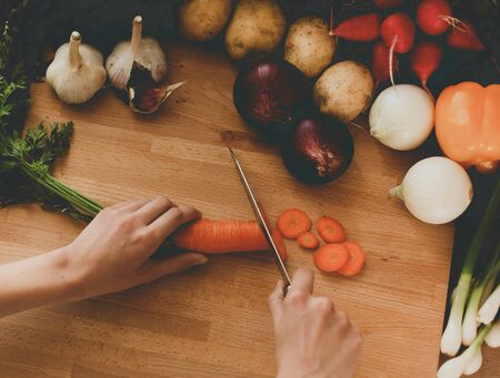 Young woman cutting vegetables in the kitchen .の写真素材
