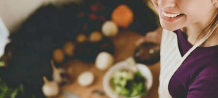 Young woman eating fresh salad in modern kitchen .の写真素材