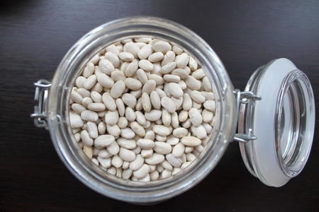 Dried white beans in a glass jar on the table for cooking