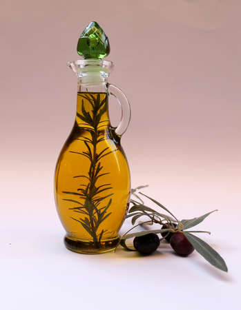 Olive oil in a glass bottle and olive branch with fruits on a light backgroundの写真素材
