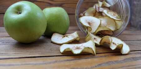Dried apples slices and green fresh apples on a wooden tableの写真素材