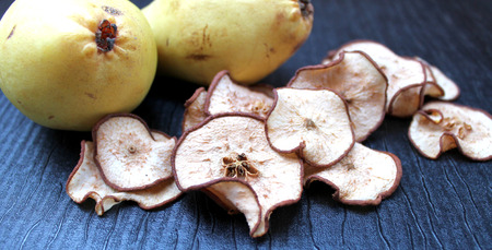 Dried pear slices on the table and fresh whole fruitsの写真素材