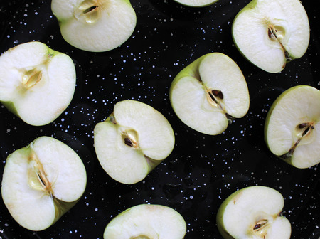 Aapple halves on a black tray before bakingの写真素材