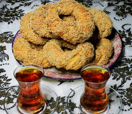 Turkish cookies with sesame seeds on a plate and two glasses of tea