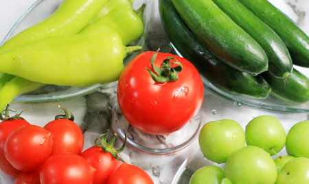Tomatoes, cucumbers, peppers and grapes on a glass tableの写真素材