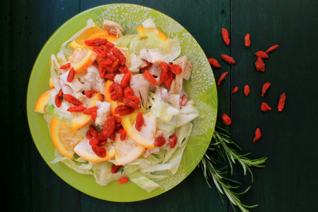 salad with chicken and tomatoes on a green plate on a wooden backgroundの写真素材