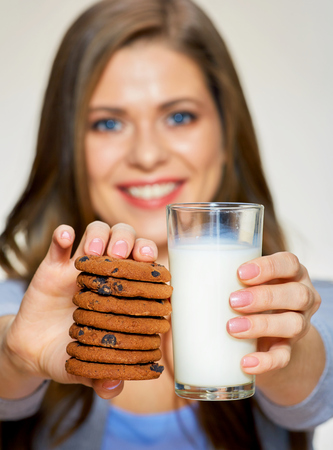 Smiling woman holding milk glass with cookies. isolated portrait.の写真素材