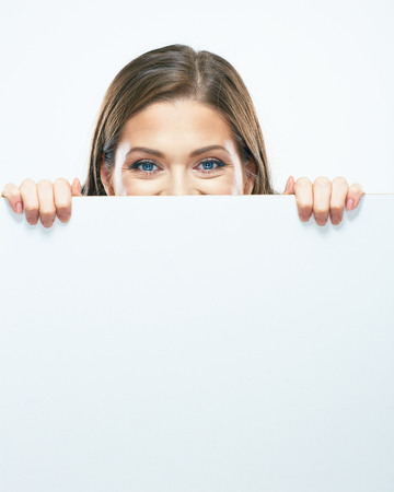 Woman looks out from behind white blank sign board.の写真素材
