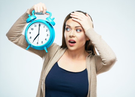 Surprised young woman hold alarm clock. White background isolated.の写真素材