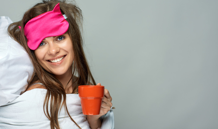 Woman with eye blindfold mask drinking coffee. Isolated portrait.の写真素材