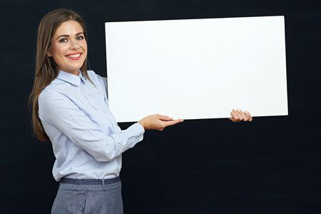 Happy business woman holding white sign board studio portrait. Black isolated.の写真素材