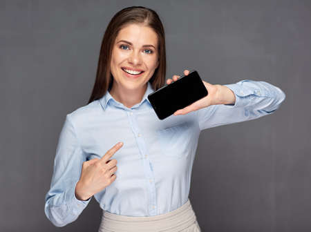 Smiling woman presenting smart phone with empty screen and pointing finger.の写真素材