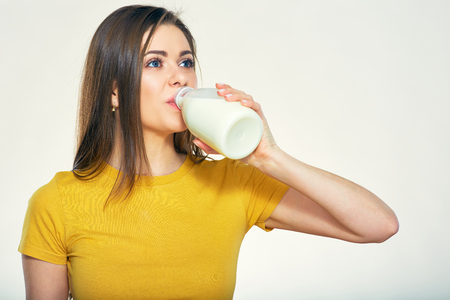 Young woman drinking milk from bottle. Isolated portrait.の写真素材