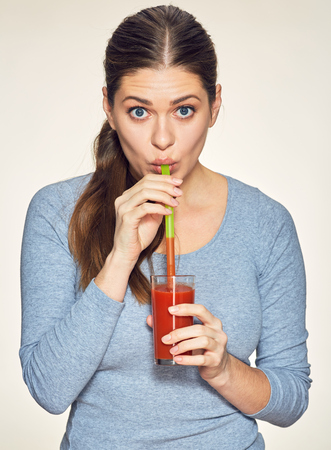 Funny young woman drink red juice. Isolated portrait.の写真素材