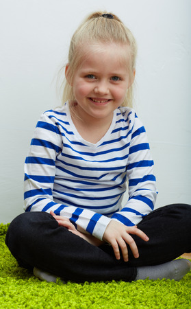 Kid girl seat on green floor.  isolated portrait.の写真素材