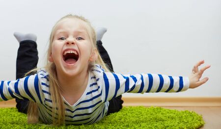 Kid girl lying on green floor.の写真素材