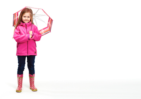 Portrait of girl child wearing pink clothes with umbrella. Isolated white studio background.の写真素材