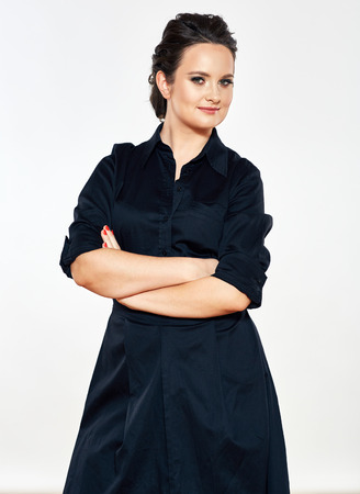 Smiling business woman standing against isolated gray background. Female model in black dress.の写真素材