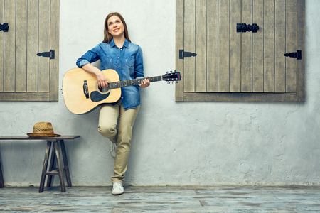 Portrait of smiling woman holging guitar on street.