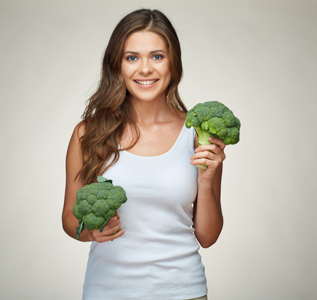 sporty smiling woman holding green vegetable. isolated studio portrait.の写真素材