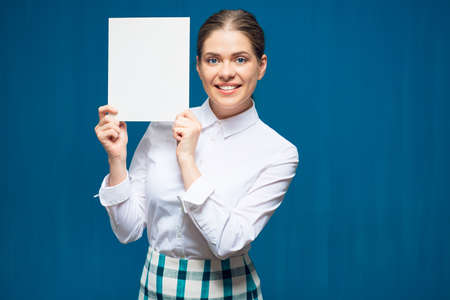 Smiling woman wearing white shirt holding advertising sign board. Portrait on blue background.の写真素材