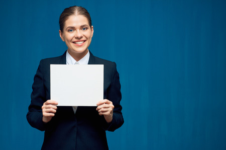 Smiling business woman holding sign card. Portrait on blue background.の写真素材