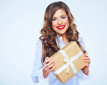 Smiling woman with long curly hair holding paper gift box. White shirt.の写真素材