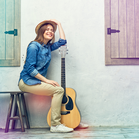 Womann sitting on street bench with guitar.の写真素材