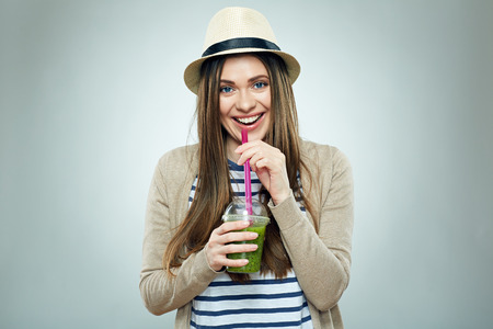 Beautiful woman drinking green smoothie juice. Casual style clothes. Isolated portrait.の写真素材