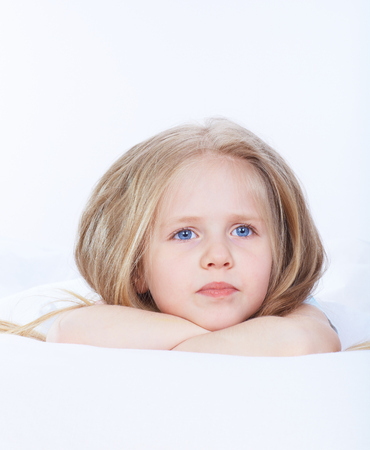 Kid girl lie on bed. Blonde girlの写真素材