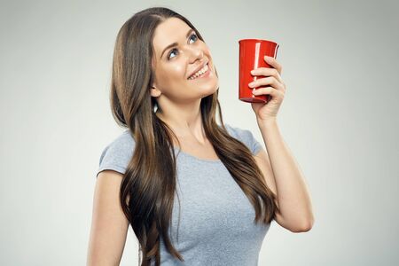 Smiling girl holding red coffee cup looking up. Isolated portrait.の写真素材