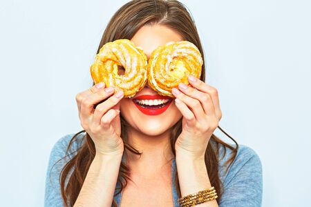 Portrait of smiling woman with two cakes in their eyes. Female young model.
