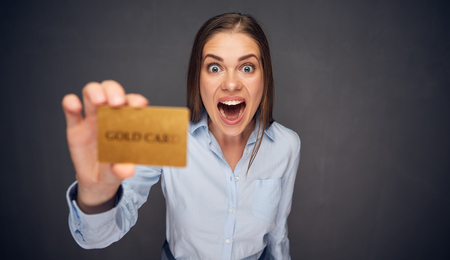 Surprised woman with open mouth holding credit card. Funny face isolated portrait.の写真素材