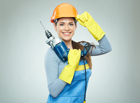 Smiling woman wearing helmet holding drill tool. Isolated portrait.の写真素材
