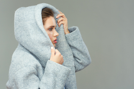 girl wears large deep coat hood. fashion style isolated portrait.の写真素材