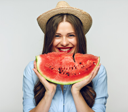 Mexican style hat wearing smiling woman eating watermelon.  isolated on white background.の写真素材