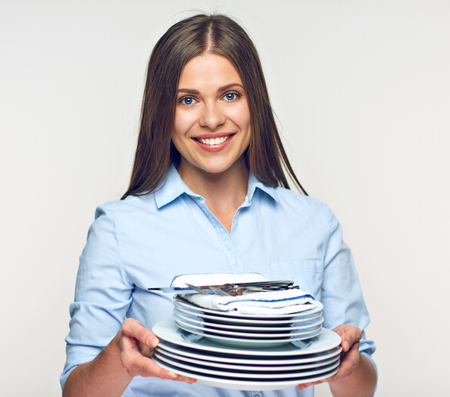 Smiling woman holding white crockery set. Girl waiter portrait.の写真素材