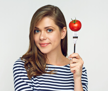 Smiling woman holding tomato on fork. Isolated portrait with dieting concept.の写真素材