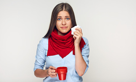 Sickness woman holding red cup blow up nose in paper tissue. Isolated portrait on white.の写真素材