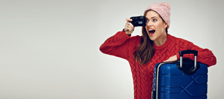 Happy woman traveler with travel case taking pictures with camera. Isolated portrait.の写真素材